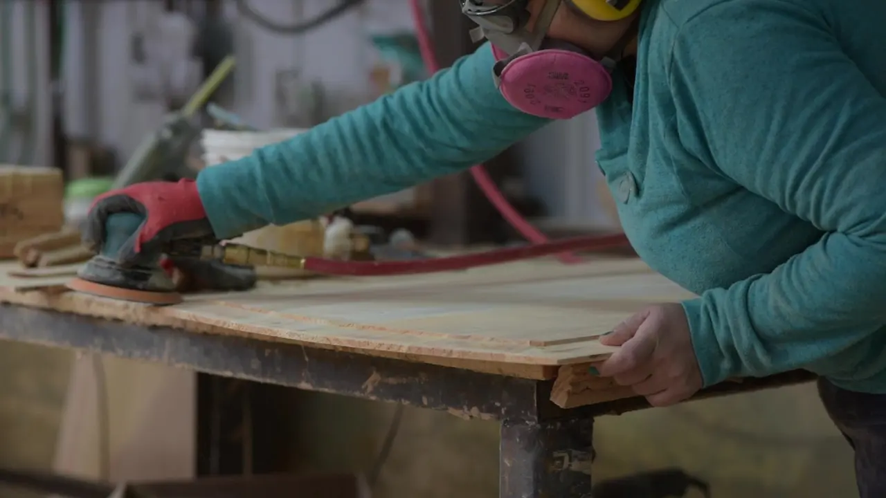 Detalle de manos lijando una superficie de madera