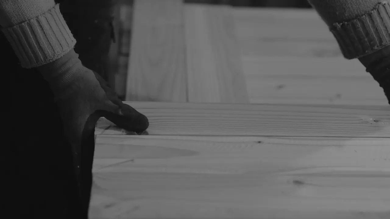 Mano revisando la veta de un listón de madera
